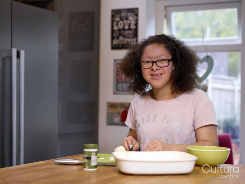 Portrait of smiling girl with Down Syndrome preparing food in kitchen