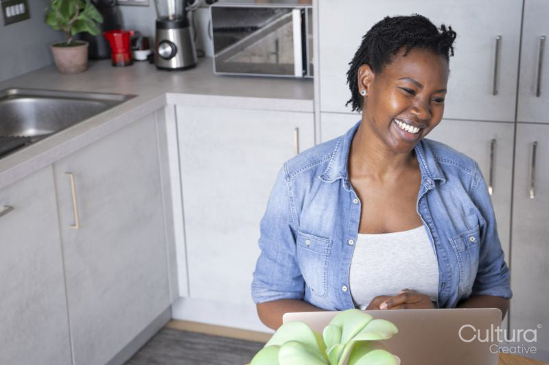 Smiling pregnant woman using laptop in kitchen