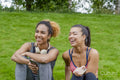 Smiling women in sportswear sitting on lawn