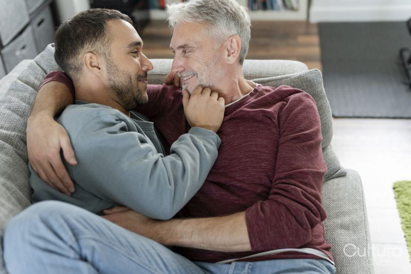 Smiling male couple hugging on sofa at home