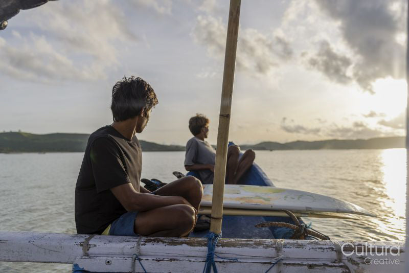 Indonesia, Lombok, Surfers looking at sea view from boat at sunset