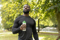 Portrait of smiling athlete man holding water bottle after workout in park