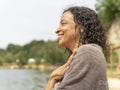 Portrait of smiling woman wrapped in towel by lake