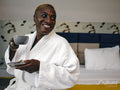 Smiling mature woman in bathrobe drinking coffee in hotel room
