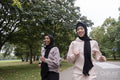 Two smiling women in hijabs jogging in park