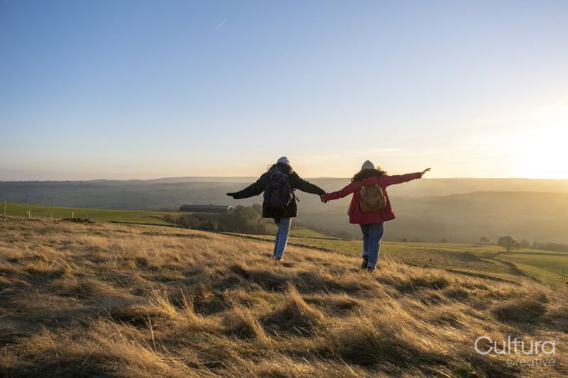 Female hikers holding hands in rural landscape