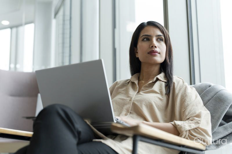 Businesswoman with laptop sitting in office lobby