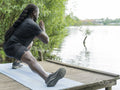 Man practicing yoga by lake