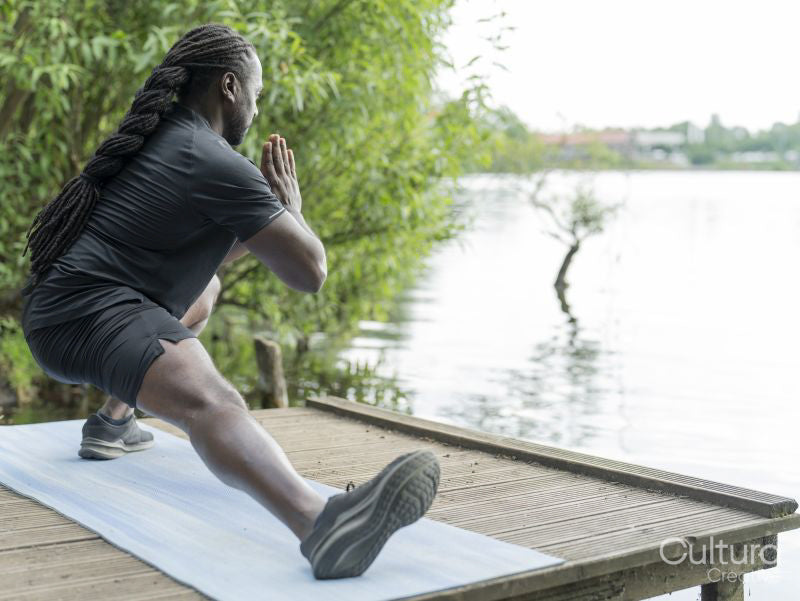 Man practicing yoga by lake