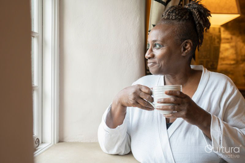 Senior woman drinking tea and looking through window