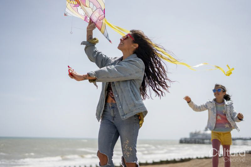 Mother and daughter flying kite on beach