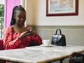 Smiling woman in red dress holding smart phone at cafe table