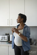 Pregnant woman holding tea cup in kitchen