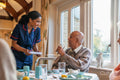 Nurse talking with senior man during dinner at cafeteria in nursing home