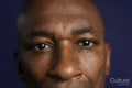 Close-up o serious man looking at camera against purple background