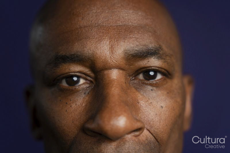 Close-up o serious man looking at camera against purple background