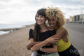 Female couple hugging on beach