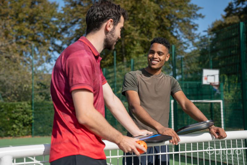 Smiling men talking in pickleball court