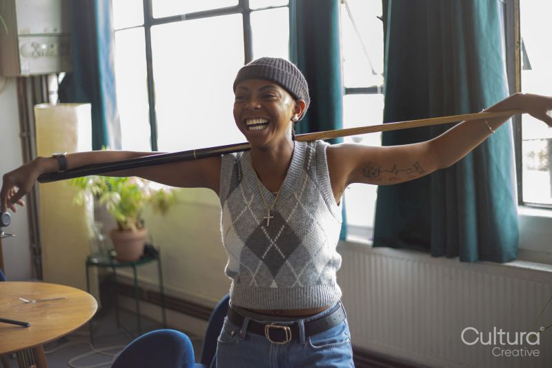 Laughing young woman holding pool cue at home