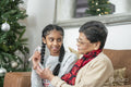 Girl with grandmother holding rosary beads and cross at Christmas tree