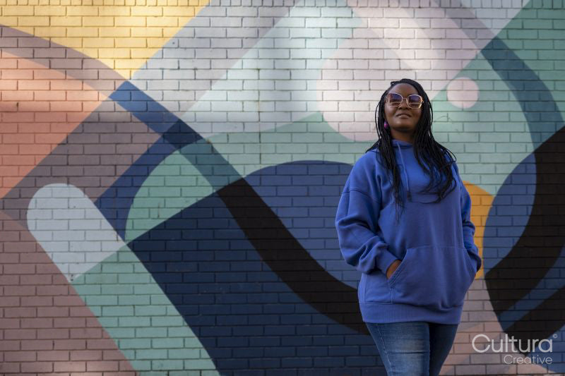 South Yorkshire, Smiling woman with braided hair against colorful wall