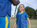 Girl in soccer uniform receiving medal from coach