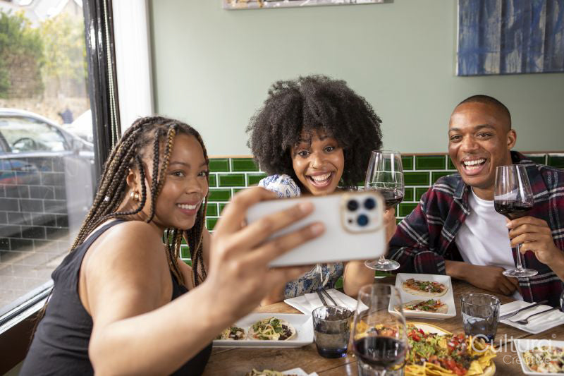 Smiling friends taking selfie at restaurant table