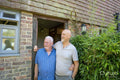 Smiling senior male couple standing in front of house