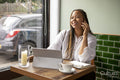 Smiling woman with laptop and smart phone at cafe table
