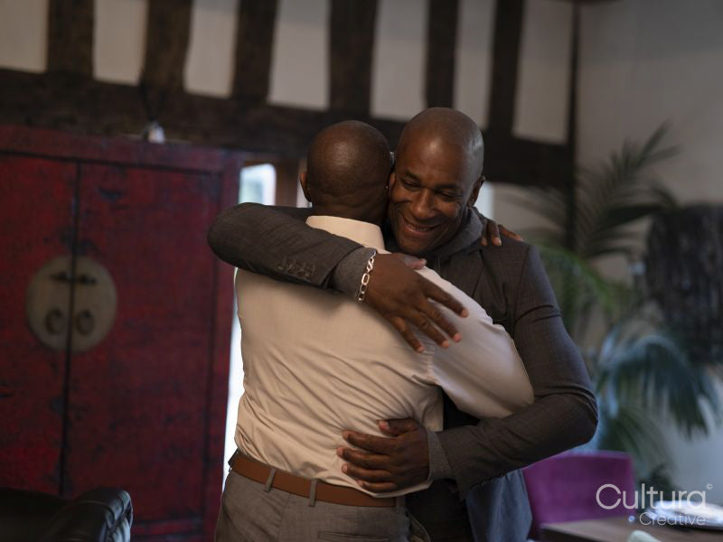 Smiling mature brothers hugging at home