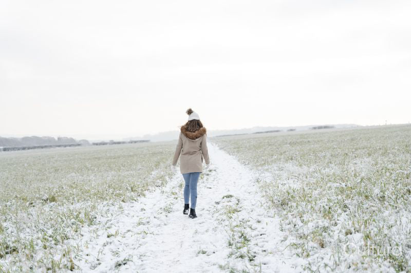 Rear view of woman walking in snowy field