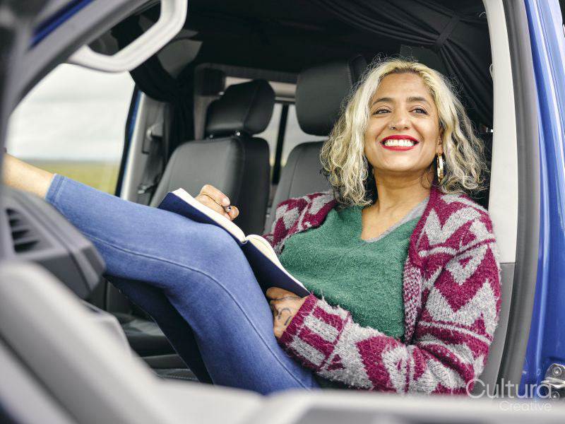 Woman sitting in van and writing in note pad