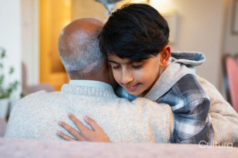 Boy hugging grandfather during visit in nursing home