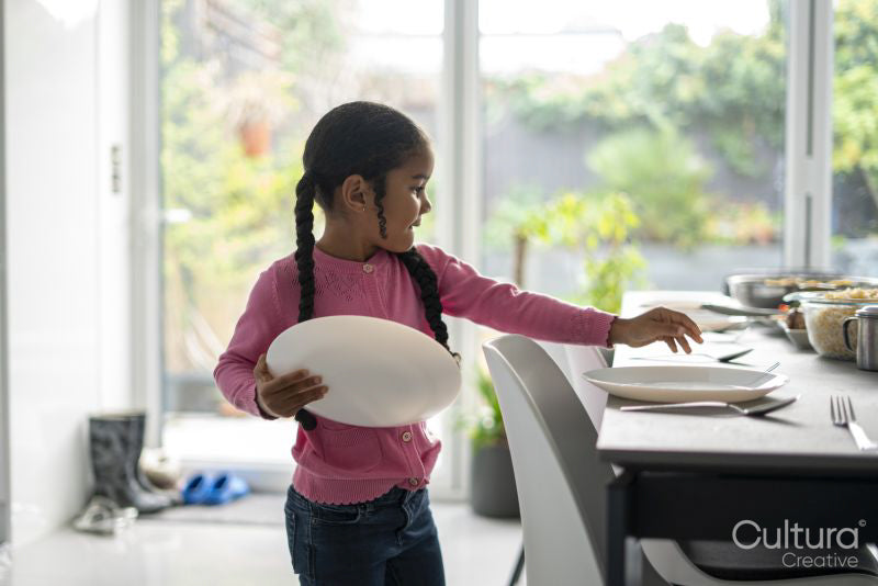 Girl placing dishes on dining table