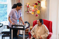Female employee serving drink to senior woman in nursing home