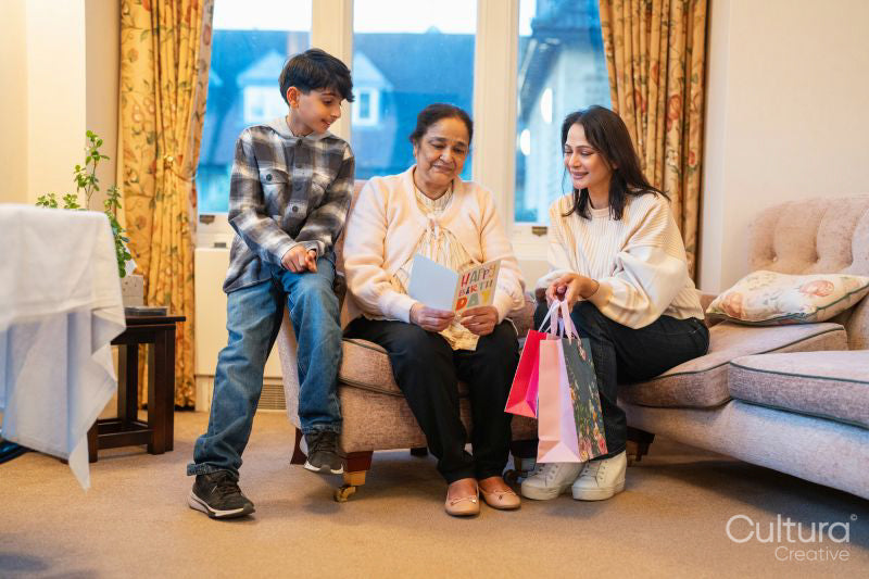 Mature woman and son visiting senior woman for birthday in nursing home