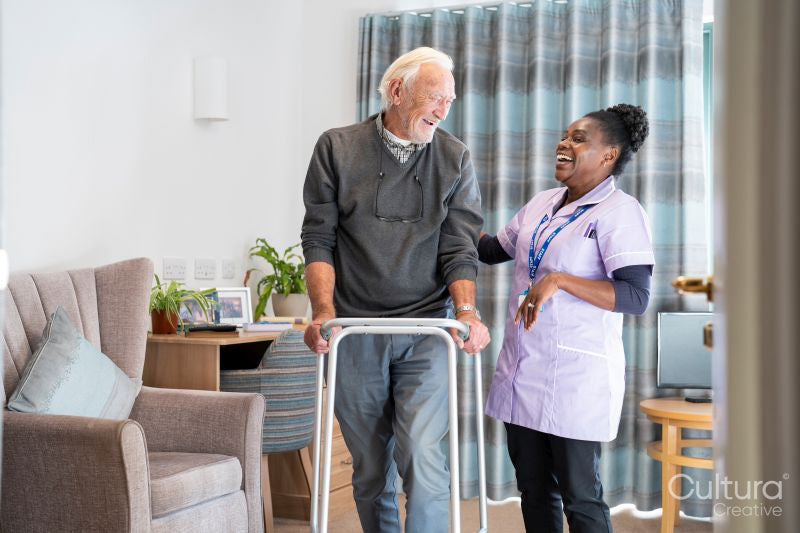 Smiling caregiver assisting senior man standing with mobility walker
