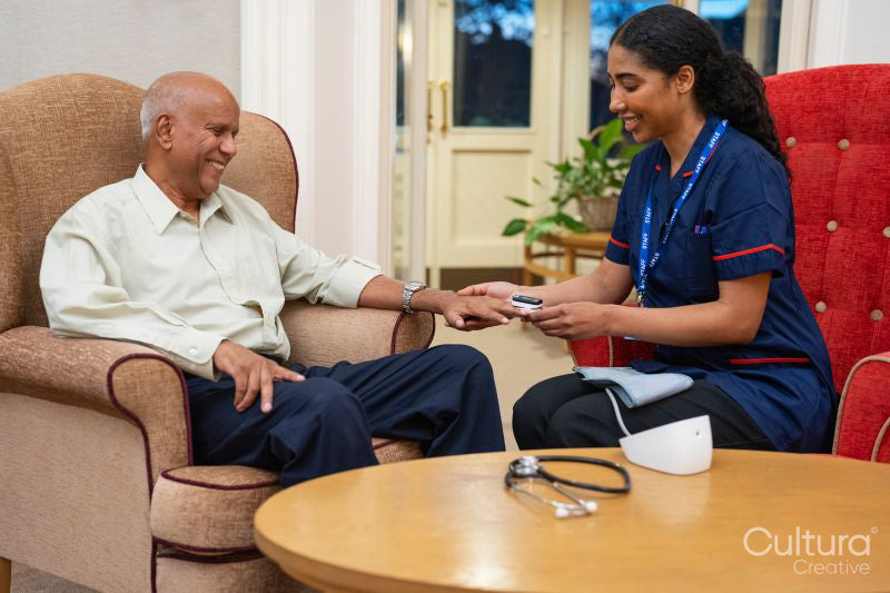 Nursing assistant using pulse oximeter on senior man at nursing home