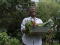 Smiling mature woman holding vegetables from garden