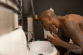 Man washing face over bathroom sink