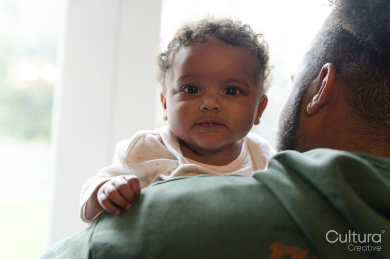 Father holding baby daughter looking at camera