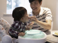 Father feeding baby son at home