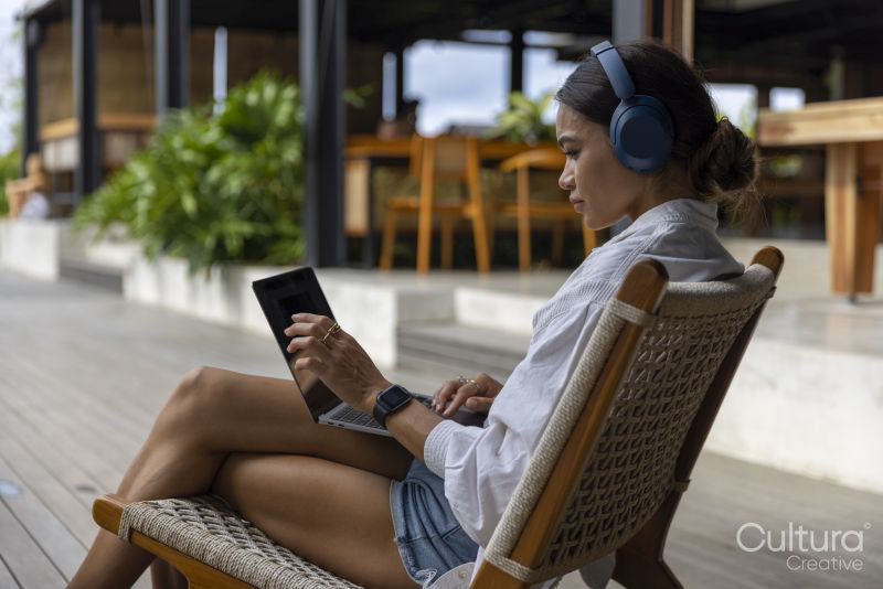 Woman using laptop with headphones at poolside