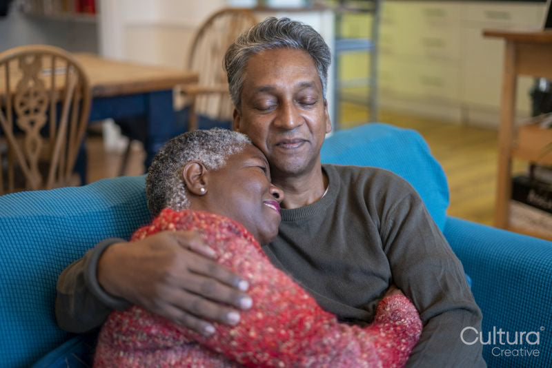Senior couple sitting on sofa and embracing