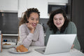 Two women looking at laptop in kitchen