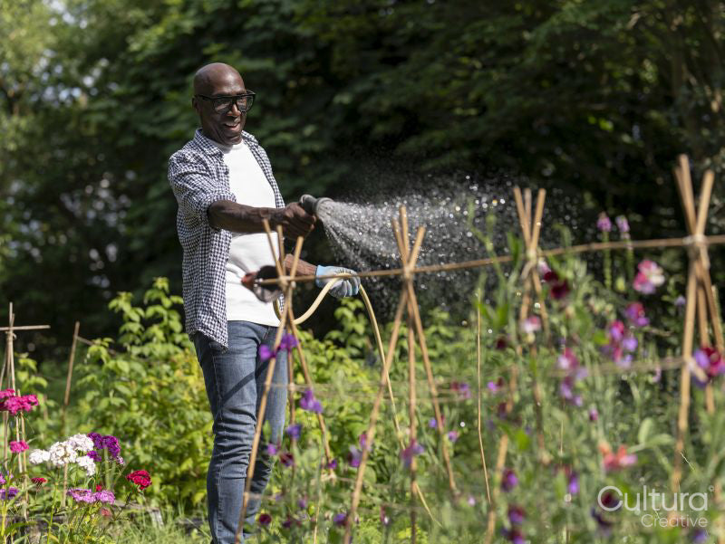 Smiling mature man watering plants in garden