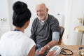Female doctor taking senior patients blood pressure in office