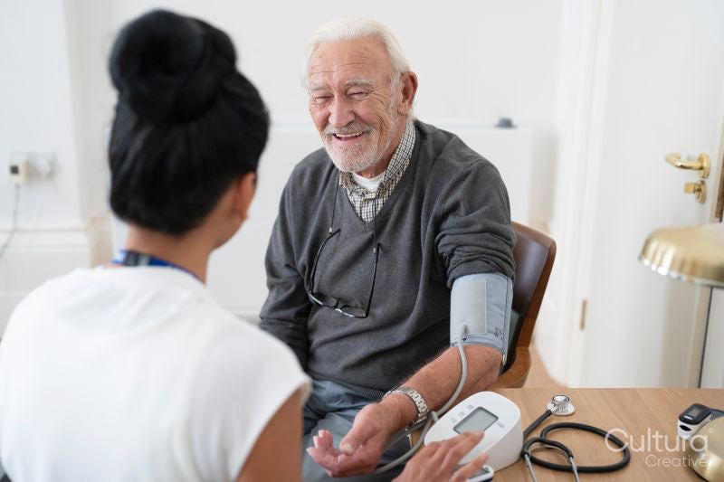 Female doctor taking senior patients blood pressure in office