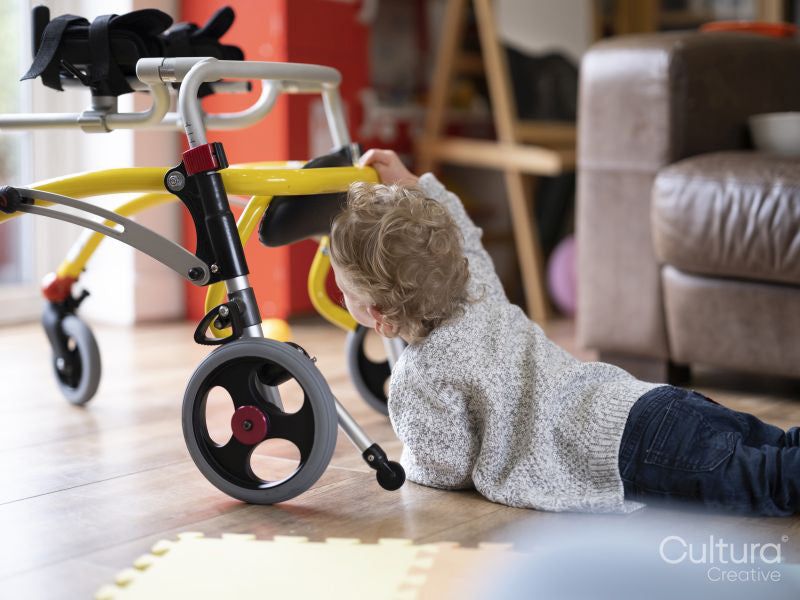 Boy lying on front and reaching to mobility walker