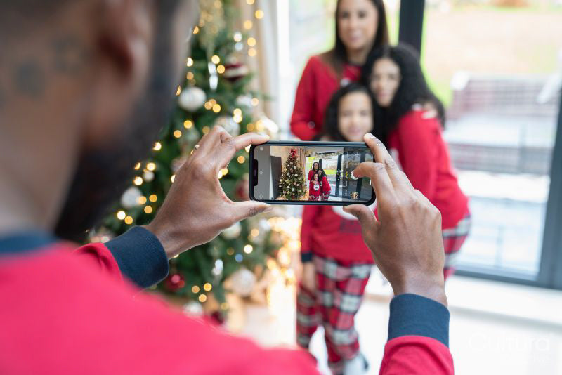 Man photographing family at Christmas tree